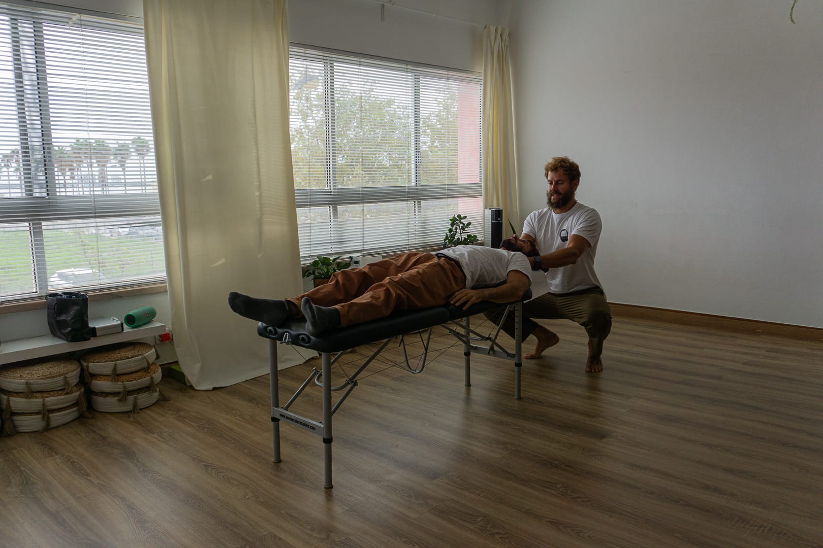 Dr. Signorini is adjusting someone that is lying on a chiropractic table and Dr. Signorini is in a squatted position to reach for the head of the patient. Chiropractor Sesimbra